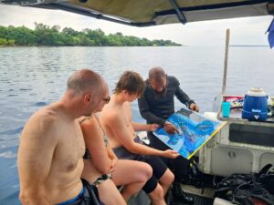 Pre dive briefing using a Reef Smart laminated chart on the dive boat of Aore Adventure Sports and Lodge.