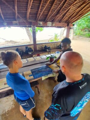 Divers study a Reef Smart laminated briefing chart of the Coolidge wreck at Pacific Divers, Vanuatu.